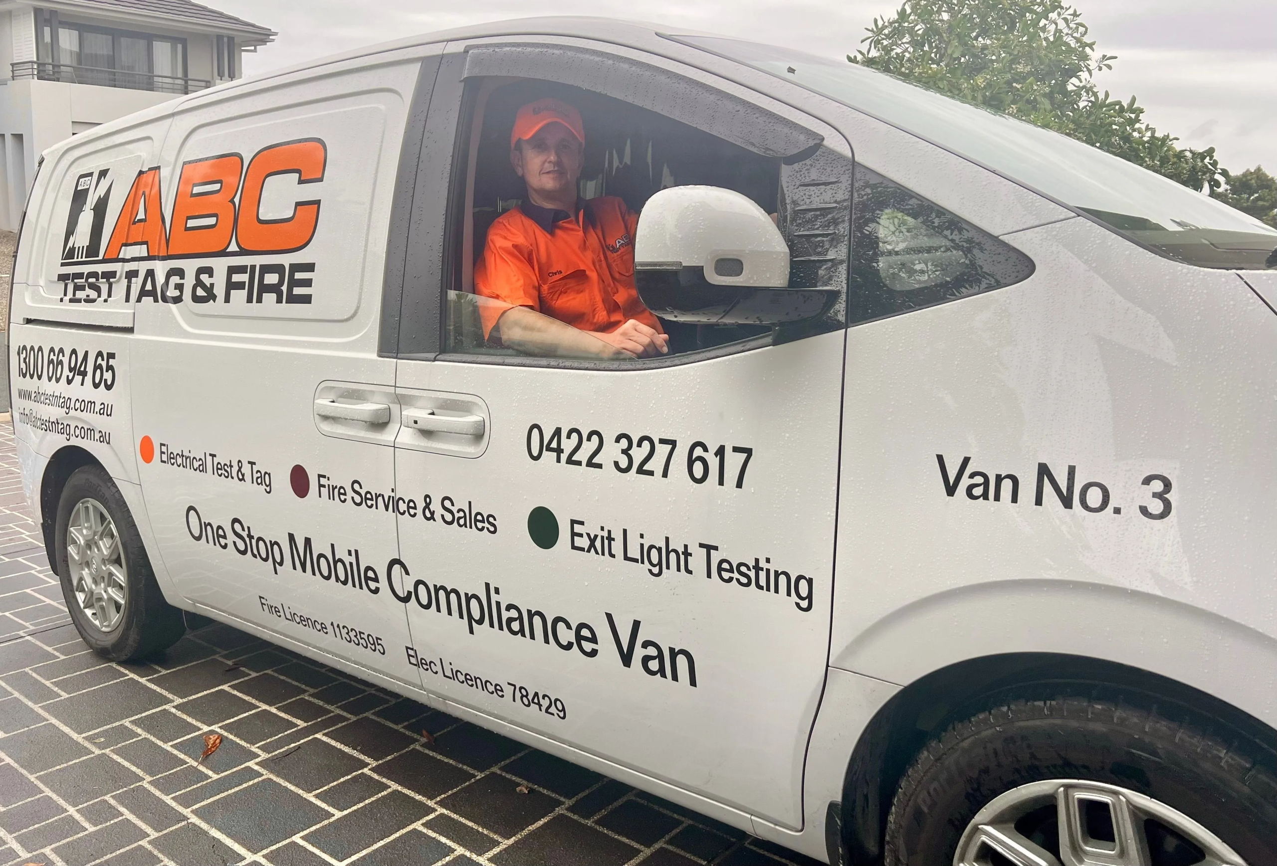 ABC Test Tag & Fire compliance van with driver, featuring electrical test and tag services, parked in a residential area.